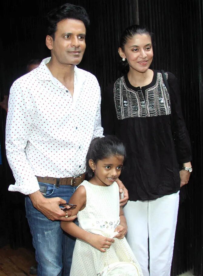 A young Ava Nayla standing between her father Manoj Bajpayee and her mother Neha during an evening out.